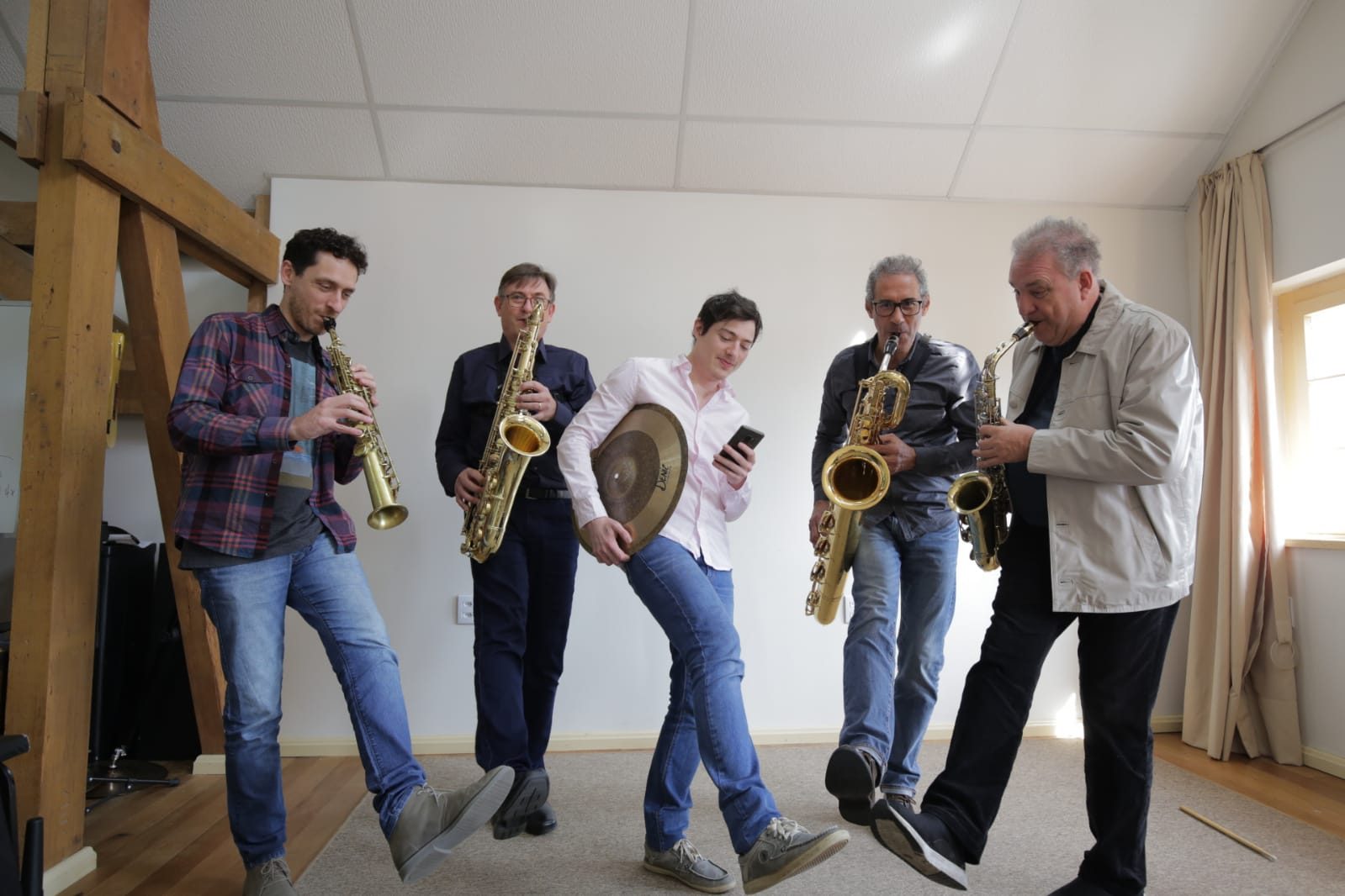 Os cinco integrantes do Barlavento tocando e levantando a perna ao mesmo tempo, em clima descontraído